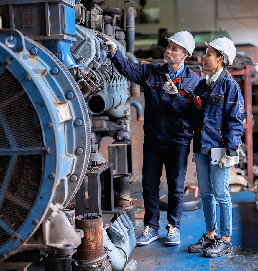 Two technicians working together and pointing at machinery