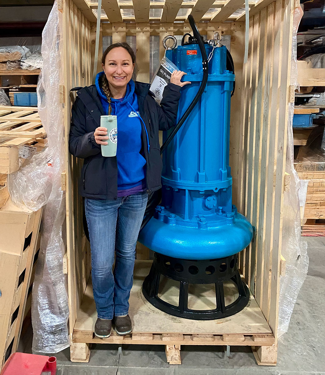 Ski Pumps employee Sarah Towle standing next to a large blue Ski Pump